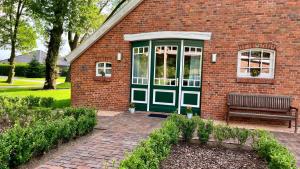 a brick house with a green door and a bench at Ferienwohnung Marita 35681 in Uplengen