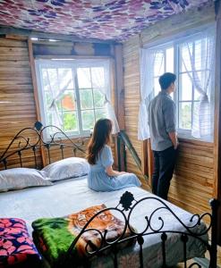 a man and a girl sitting on a bed looking out the window at Roots Casa Rústica in Valle Hornito