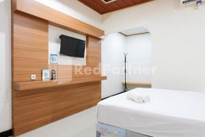 a bedroom with a tv on the wall and a bed at As Waru Hotel RedPartner in Palang-Putih