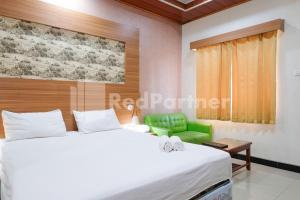 a bedroom with a bed and a green chair at As Waru Hotel RedPartner in Palang-Putih