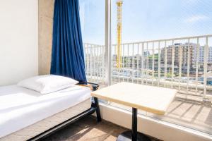a bed and a table in a room with a window at Sakura Hostel Asakusa in Tokyo