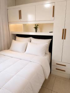 a bedroom with a white bed and white cabinets at Refúgio Beira Mar Na Praia da Tartaruga in Rio das Ostras