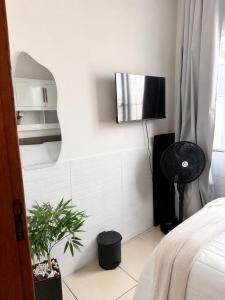 a bedroom with a tv on a white wall at Refúgio Beira Mar Na Praia da Tartaruga in Rio das Ostras