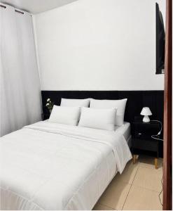 a bedroom with a large bed with white sheets at Refúgio Beira Mar Na Praia da Tartaruga in Rio das Ostras