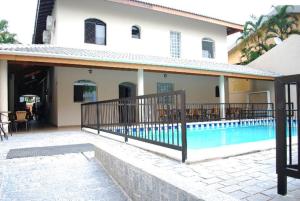uma casa com piscina ao lado de um edifício em Parque Suites Com Ar Condicionado Piscina e Estacionamento no Guarujá