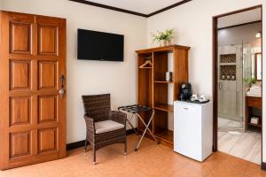 a room with a door and a chair and a refrigerator at Hotel Espadilla Gardens in Quepos +20 photos