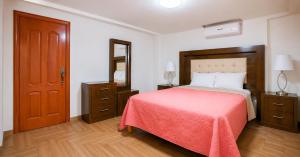a bedroom with a large bed with a red blanket at Hotel Plaza Tapatia in Guadalajara +2 photos