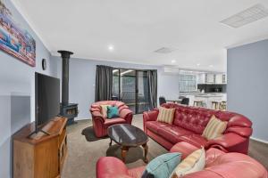 a living room with two red couches and a fireplace at The Brynes Hideaway - On Brynes Road in Goolwa