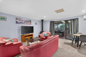 a living room with two red couches and a television at The Brynes Hideaway - On Brynes Road in Goolwa