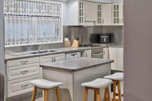 a kitchen with white cabinets and bar stools at The Brynes Hideaway - On Brynes Road in Goolwa