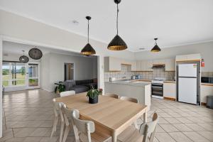 a kitchen and living room with a wooden table and chairs at Barnacles Shack - Mills Road in Hindmarsh Island