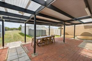 a patio with a table and chairs under a roof at Barnacles Shack - Mills Road in Hindmarsh Island
