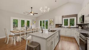 a kitchen with white cabinets and a dining room with a table at Poolside Paradise by AvantStay in Sherrills Ford