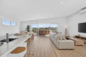 a white living room with a couch and a kitchen at Marina Breeze - Excelsior Pde in Hindmarsh Island