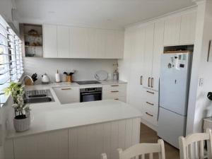 a kitchen with white cabinets and a white refrigerator at 2 Shore Ct - Shore Thing in Goolwa South
