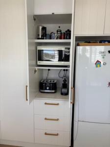 a kitchen with a white refrigerator and a microwave at 2 Shore Ct - Shore Thing in Goolwa South