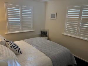 a bedroom with a bed and two windows at 2 Shore Ct - Shore Thing in Goolwa South +30 photos