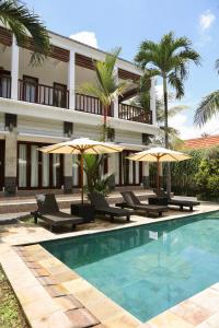 a resort with a swimming pool with chairs and umbrellas at Umanara Ubud in Ubud