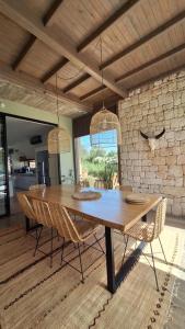 a dining room table with chairs and a stone wall at Villa Terra Akal in Essaouira