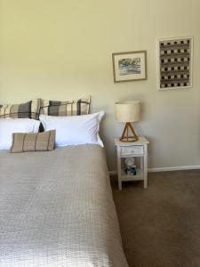a bedroom with two beds and a table with a lamp at Lulu's Cottage by Native Forest in Waimauku