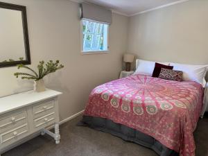 a bedroom with a bed and a dresser and a mirror at Lulu's Cottage by Native Forest in Waimauku +24 photos