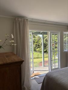 a bedroom with a bed and a sliding glass door at Lulu's Cottage by Native Forest in Waimauku