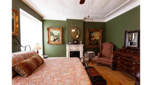 a bedroom with green walls and a bed and a fireplace at Governors Room in Cimarron