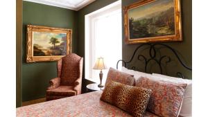 a bedroom with a bed and a chair and paintings at Governors Room in Cimarron
