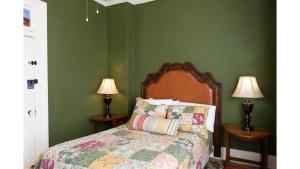 a bedroom with a bed with green walls and two lamps at Remington in Cimarron