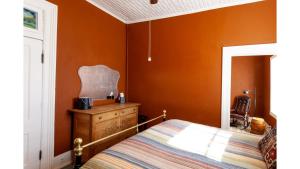 a bedroom with orange walls and a bed and a dresser at Doc Holiday in Cimarron