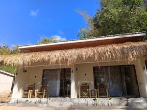 a small house with a straw roof and chairs at VIA Homestay 1 in Kuta Lombok