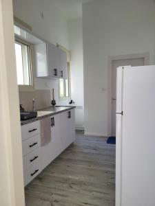 a kitchen with white cabinets and a refrigerator at Serenity Apartment in Dalia in Dāliyat el Karmil +10 photos