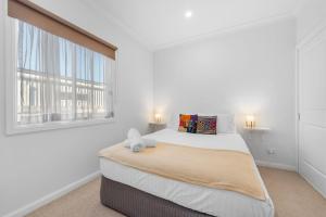 a white bedroom with a large bed and two windows at 15B Bolton Street in Berridale