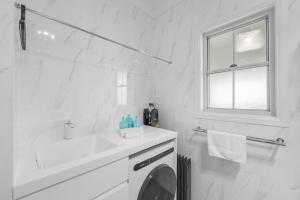 a white bathroom with a sink and a washing machine at 15B Bolton Street in Berridale +5 photos