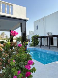 a villa with a swimming pool and flowers at Al Reef Garden in Sohar