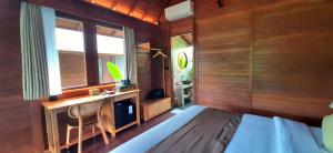 a bedroom with a bed and a desk and a window at The Woods Uluwatu in Uluwatu