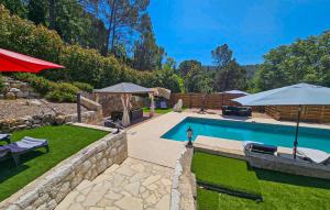 a backyard with a swimming pool with an umbrella at Nice Home In Peymeinade in Peymeinade