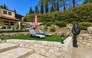 a garden with two chairs and an umbrella and a stone wall at Nice Home In Peymeinade in Peymeinade +11 photos