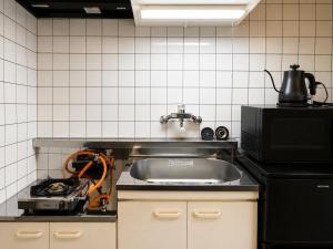 a kitchen with a sink and a microwave at Palette Kuhonji in Kumamoto