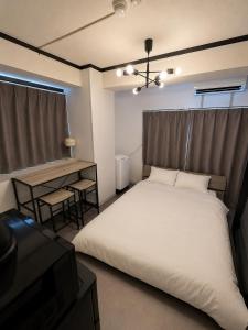 a bedroom with a large white bed and a desk at Palette Kuhonji in Kumamoto