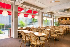 a dining room with tables and chairs and windows at Sakura Hostel Asakusa in Tokyo