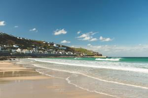 a beach with the ocean and houses on a hill at The Old Success Inn in Sennen Cove