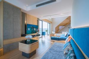 a living room with a blue couch and a tv at Homestay Alacarte - Icon40 - New Life - Villa Lotus in Ha Long