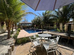 a patio with a table and chairs next to a pool at Chalés Farol Village in Fortim