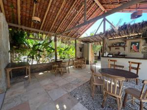 a patio with tables and chairs and a bar at Chalés Farol Village in Fortim