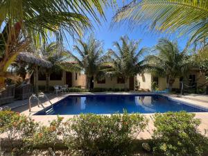 a swimming pool with palm trees in a resort at Chalés Farol Village in Fortim
