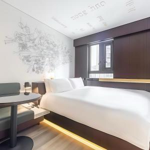 a bedroom with a large white bed and a table at CitiGO Hotel Shanghai Xujiahui in Shanghai