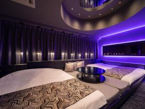 two beds in a room with purple lighting at FUN3 ﾌｧﾝｽﾘｰ -Adult Only- in Yokohama