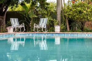 2 sillas sentadas junto a una piscina en Admirals Lodge Guest House, en Port Elizabeth