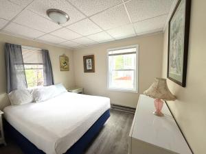 a bedroom with a white bed and two windows at Crosswinds Motel in Old Orchard Beach +173 photos